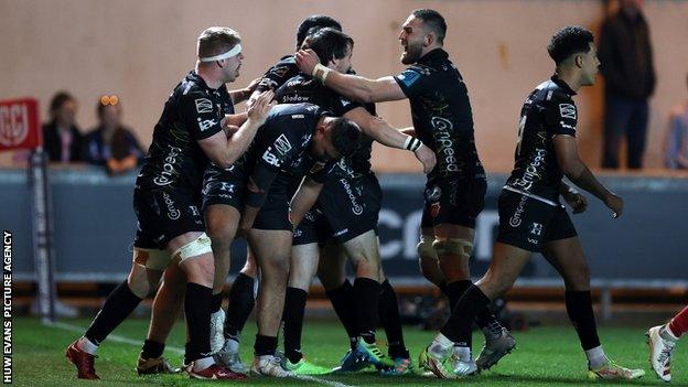 Dragons players celebrate the victory against Scarlets