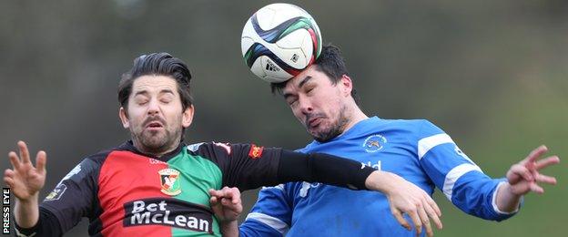 Glentoran's Curtis Allen fights out an aerial duel with Ballinamallard's Emmet Friars