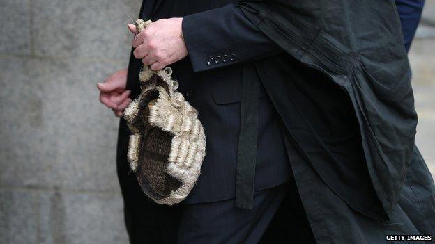 A barrister holds his wig as he arrives at The Old Bailey on 27 July 2015