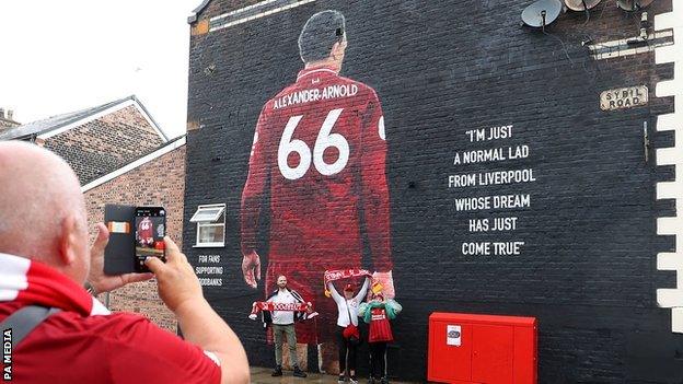 Liverpool fans have their picture taken in front of the Trent Alexander-Arnold mural