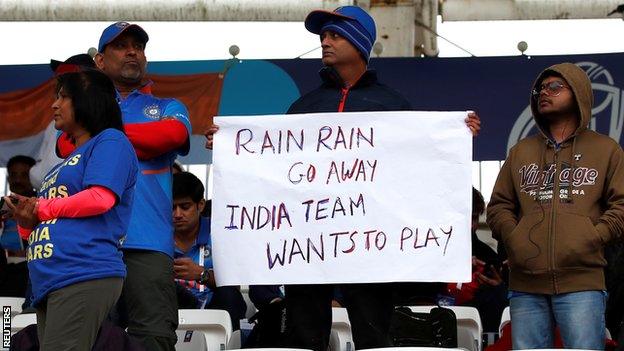 An India fan holds a sign saying 'Rain rain go away India team wants to play'