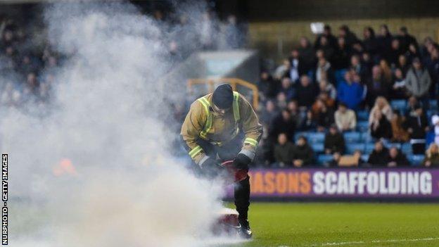 Three flares were thrown onto the pitch at Millwall's New Den on Saturday, apparently from protesting West Brom fans