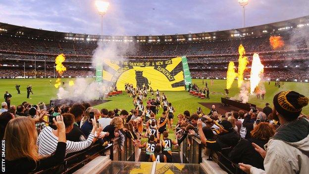 Fans cheer on Richmond players as they run onto the field at the MCG before their game against Carlton in 2019