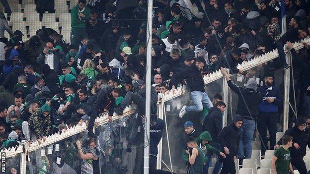 Fans climb a fence