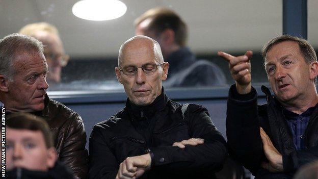 Bob Bradley checks his watch while watching Swansea under-23 alongside Alan Curtis and Huw Jenkins