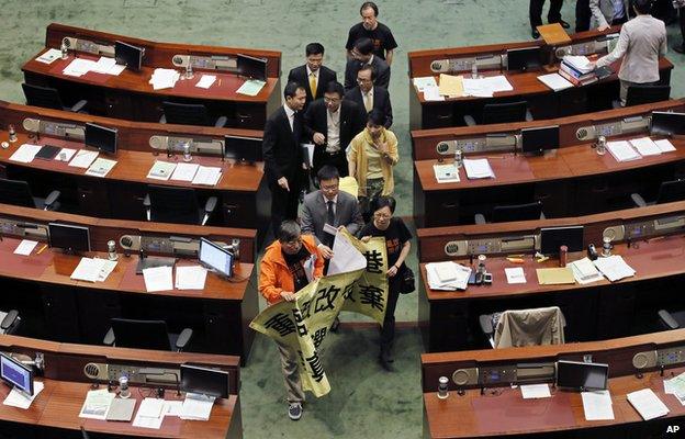 Pro-democracy lawmakers walk with a banner that reads "Reopen political reform to protect Hong Kong, never give up to fight for true universal suffrage"