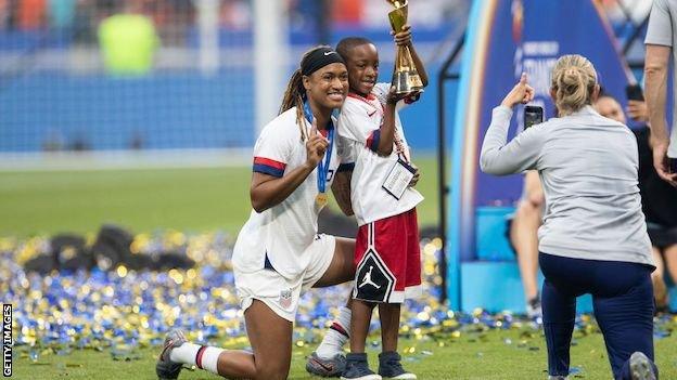 Jessica McDonald with her son Jeremiah as he holds the Women's World Cup trophy