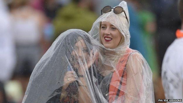 Two festival-goers in a rainmac at Weston Park