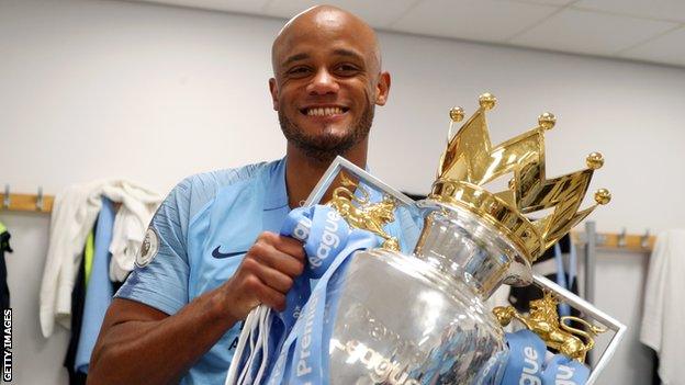 Manchester City captain Vincent Kompany holds up the Premier League trophy in the dressing room