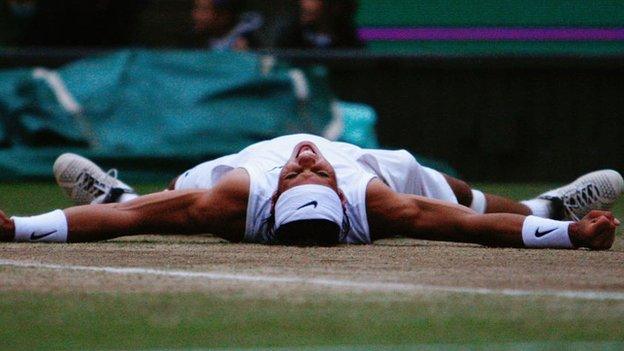 Rafael Nadal lies on his back with his arms spread out as he celebrates his first Wimbledon triumph