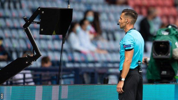 A referee using VAR during Euro 2020