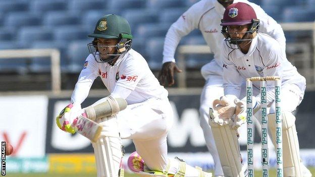 Bangladesh's Mushfiqur Rahim reverse-sweeps, watched by West Indies keeper Shane Dowrich