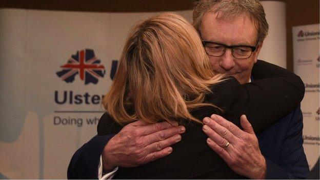 mike nesbitt hugs someone while stepping down