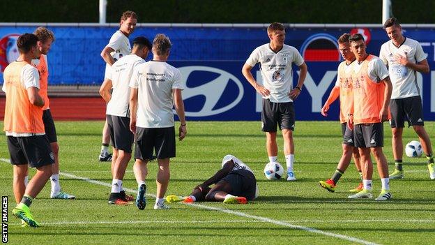 Antonio Rudiger lies on the ground holding his knee after being injured in traing with Germany