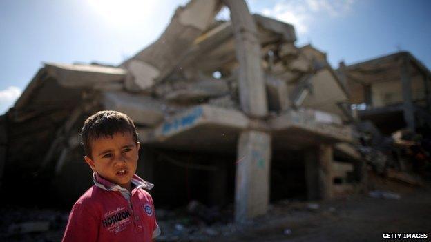 A Palestinian boy plays outside bombed buildings in Gaza City