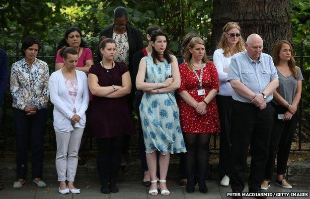 People observe a minute's silence at a memorial to victims