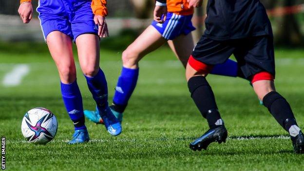 Women in Germany playing football. Only their legs and the ball are visible in the photo.