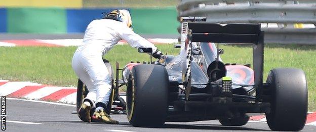 McLaren's Fernando Alonso pushes his car after it broke down in qualifying at the Hungarian Grand Prix