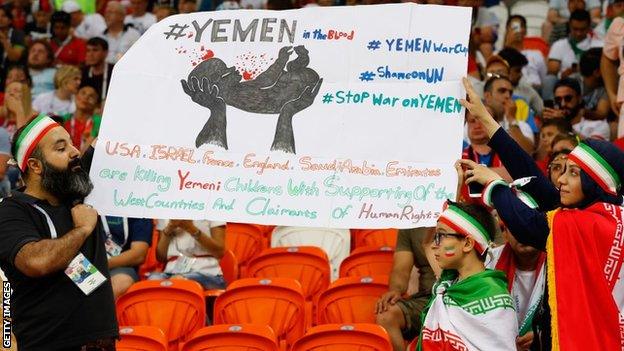 Iran supporters carry a placard against the war on Yemen, during the World Cup match between Iran and Portugal in Saransk, Russia