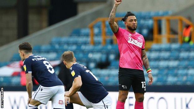 Derby County's Colin Kazim-Richards raises his fist as Millwall players take a knee before kick-off