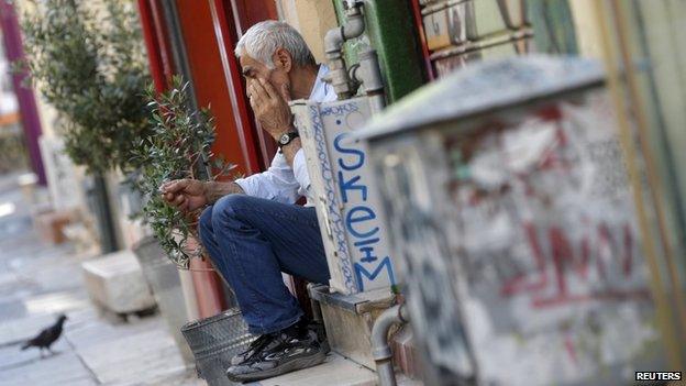 A vendor sits on the steps in front of his shop in central Athens