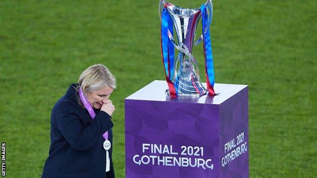 Emma Hayes walking past the Champions League trophy