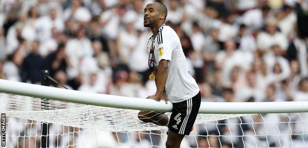 Denis Odoi celebrates Fulham's promotion by climbing on the Wembley crossbar