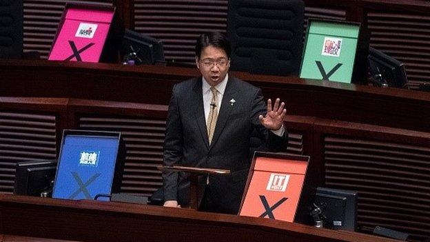 Hong Kong pro-democracy lawmaker Charles Mok addresses the city's legislature next to placards symbolising a vote against the government's controversial electoral roadmap, in Hong Kong on June 18, 2015