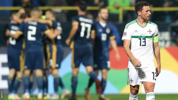 Dejection for Corry Evans as the hosts celebrate Edin Dzeko's opening goal in Sarajevo