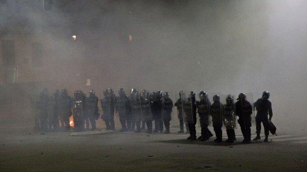 Kosovo police officers in riot gear stand in a cloud of tear gas in Kosovo capital Pristina as clashes broke out after the arrest of a prominent opposition politician Albin Kurti on Monday, Oct. 12, 2015.