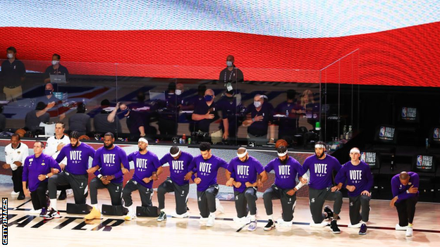 Lakers players kneel during the national anthem while wearing t-shirts emblazoned with 'vote'