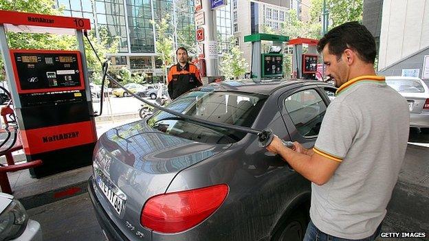 A fuel attendant fills a car at a petrol station in the Iranian capital Tehran on 25 May, 2015. The Iranian government has lifted the quota of 60 litres of subsidised fuel for individuals,