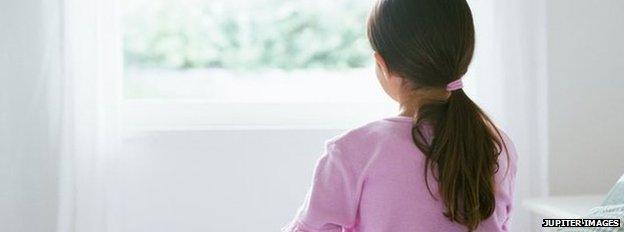 Young female child (girl, youth) sitting alone on the edge of a bed