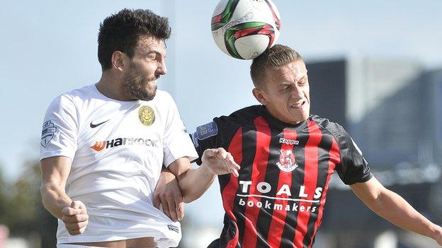 Carrick's Conor McCloskey and Crusaders midfielder Matthew contest a high ball