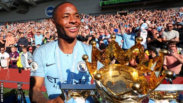 Manchester City forward Raheem Sterling smiles as he holds up the Premier League trophy