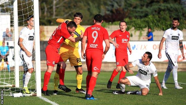 Connah's Quay Nomads' George Horan (left) and Partizan Belgrade goalkeeper Vladimir Stojkovic (centre) in a tussle