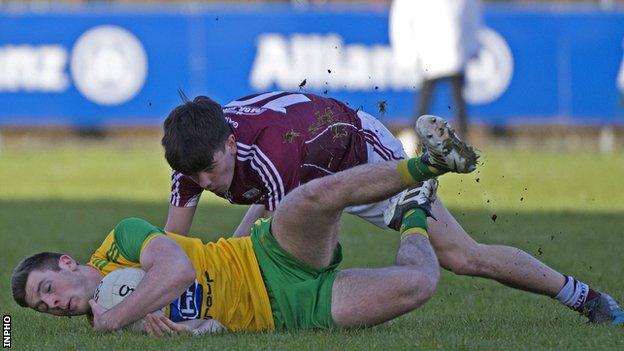 Donegal's Eoghan Ban Gallagher clings to the ball as Seán Kelly of Galway challenges