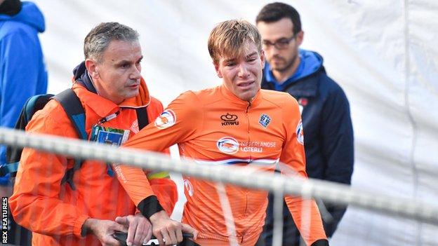 Dutch rider Nils Eekhoff is led away in tears after being told he has been disqualified from winning the under-23 men's world road race