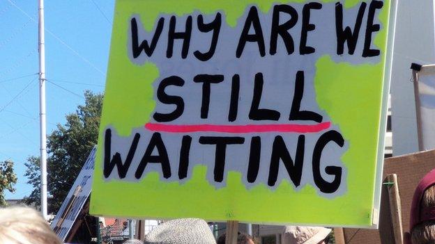 A sign held by a protester reading 'Why are we still waiting'