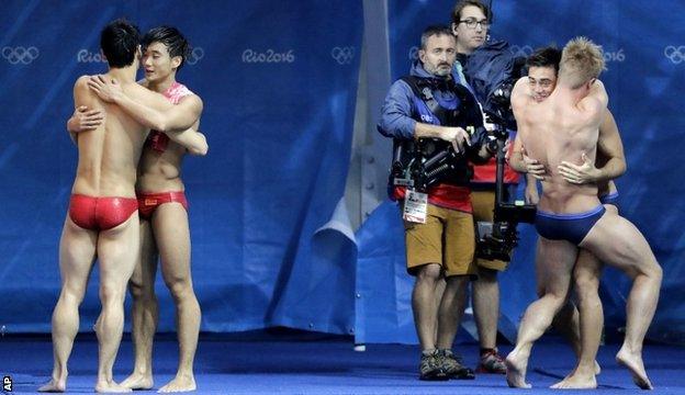 Chinese bronze medallists Cao Yuan and Qin Kai hug each other as Jack Laugher and Chris Mears celebrate