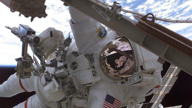 An astronaut with tools attached to their spacesuit