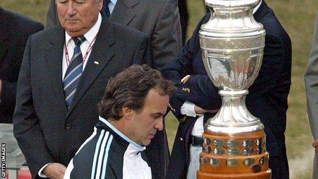 Marco Bielsa walks past the Copa America 2004 trophy