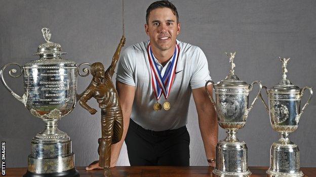 Brooks Koepka poses with trophies