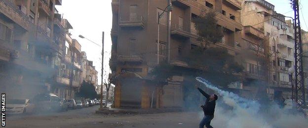 A protester in the flashpoint central Syrian city of Homs throws a tear gas bomb back towards security forces, on December 27, 2011. Syrian police used tear gas to disperse some 70,000 people who took to the streets of Homs as Arab observers visited there a day after dozens of people died in the crackdown on dissent