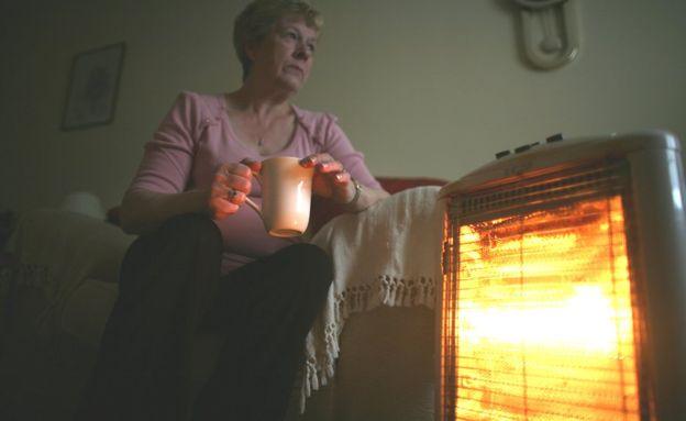 Woman sitting at heater