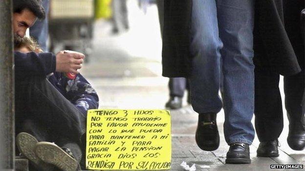 An unemployed man, holding one of his three children in his arms, seeks alms on the street on 23 July 2001 in Buenos Aires, Argentina.