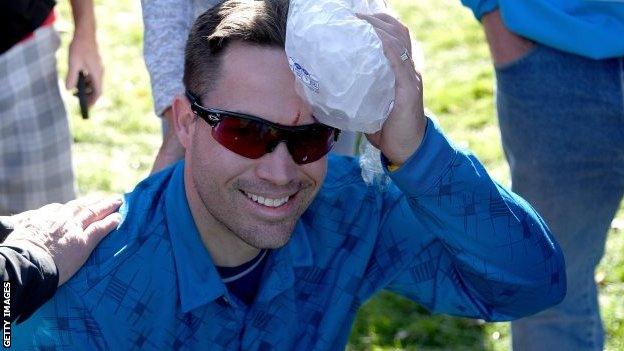 A fan holds an ice pack on his head after being hit by a stray Danny Willett drive