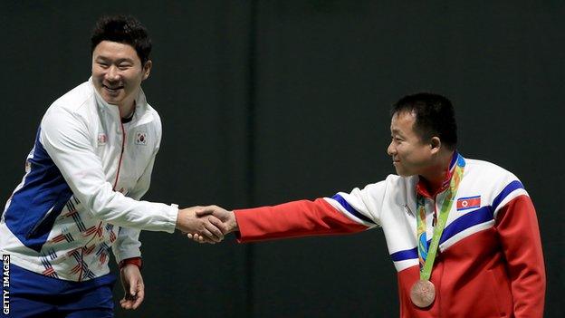 Gold medalist Jongoh Jin of Korea shakes hands with bronze medalist Song Guk Kim following the 50m pistol event