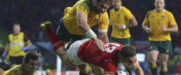 Bernard Foley (bottom left) and Ben McCalman complete a double tackle to stop Wales wing George North scoring