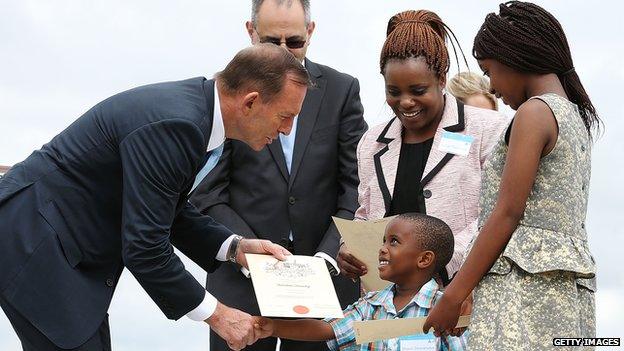 Prime Minister Tony Abbott gives certificates to the Taruvinga family from Zimbabwe at Citizenship Ceremony on January 26, 2015 in Canberra, Australia